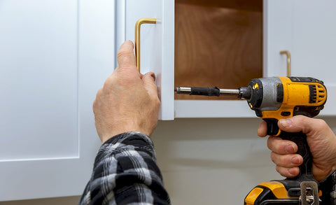 Woman replacing cabinet handles in kitchen