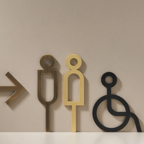 High-quality solid brass bathroom and accessibility signage in black, showcasing tactile letters and symbols, designed for durability, ADA compliance, and a sleek, modern appearance.
