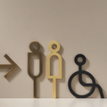 High-quality solid brass bathroom and accessibility signage in bronze, with tactile letters and symbols, designed for durability, ADA compliance, and elegant appearance in commercial or residential spaces