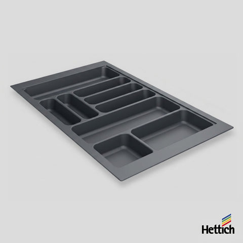 A dark gray plastic under-sink organizer tray with multiple compartments, shown at an angle on a light gray background with the Hettich brand logo in the bottom right corner.