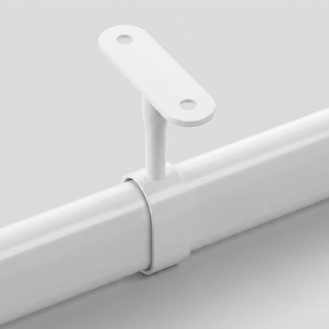 A close-up of a white wall-mounted bracket holding a white curtain rod against a light gray background.