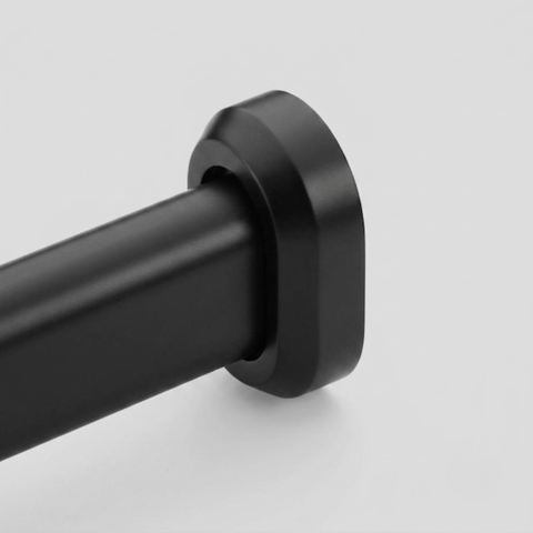 Close-up of a matte black curtain rod end with a matching round mounting bracket on a light gray background.