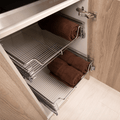 Pull-out chrome wire basket in a cabinet, showcasing space for towels, from KitchenLibrary.