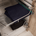 Pull-out chrome wire basket featuring neatly organized towels in a kitchen cabinet by KitchenLibrary.