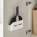 Peka white dustpan and brush holder mounted on a cupboard door, holding a dustpan and brush