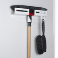 Peka Libell white broom holder mounted on a door, holding a broom and dustpan brush
