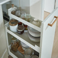 Peka Pinello Cargo white base unit pull-out with oak handle storing jars and bowls on tiered shelves in a white kitchen