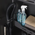 Close-up of Peka Sesam Standard anthracite shelf with cleaning bottles, folded cloths and a vacuum hose holder
