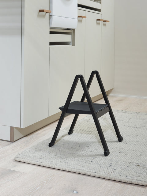 Peka Stepolo compact one-step folding stepladder in black, unfolded on a kitchen floor